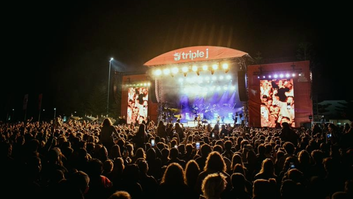 Photo of a crowd infront of a stage covered in triple j branding