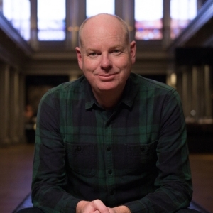 Tom Gleeson sits inside a museum space.