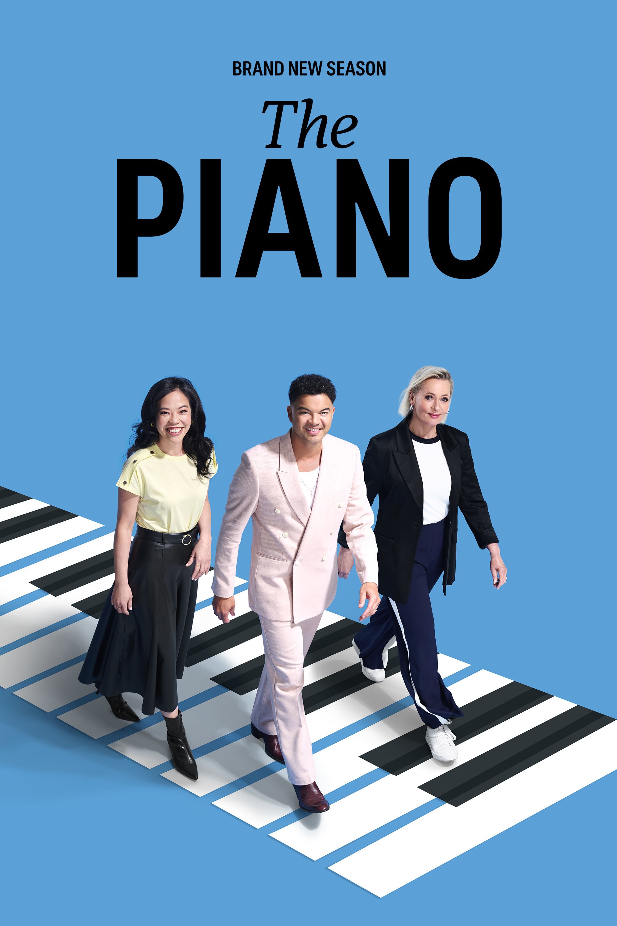  Three people walk toward the camera along a path designed to look like oversized piano keys. The person in the center wears a pale pink suit, flanked by two others in stylish, professional attire against a bright blue background. The title The PIANO is centered at the top in black text.