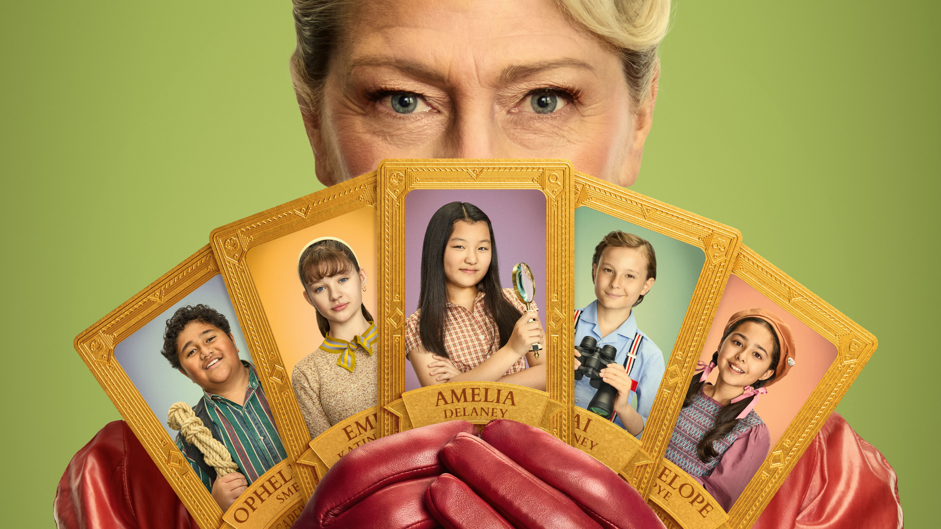 A close-up of a person in red leather gloves holding a fan of five gold-bordered character cards, obscuring the lower half of their face. Each card features a different child holding an item like a rope, magnifying glass, or binoculars. The person’s eyes gaze directly forward against a solid green background.