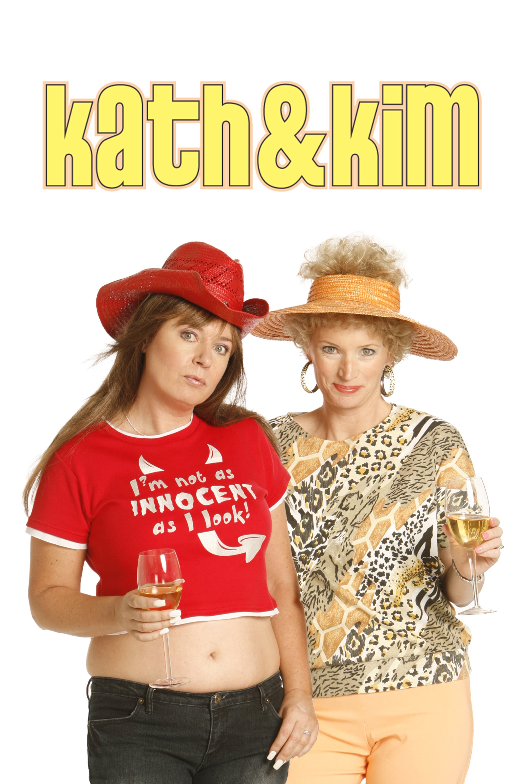 Iconic duo Kath and Kim in flamboyant outfits and hats, holding wine glasses against a plain white background.