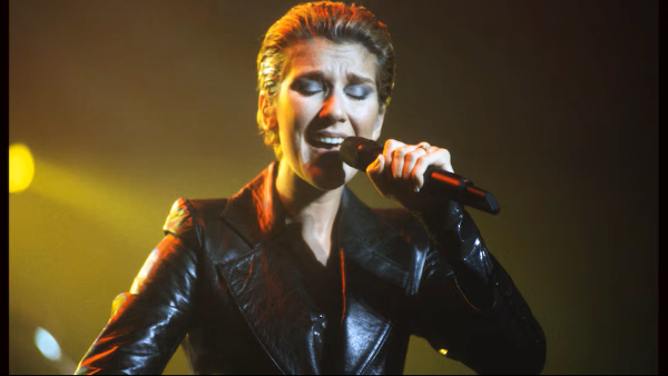 Canadian music artist Celine Dion singing on a stage lit by yellow lights